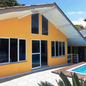 uma casa amarela com uma piscina em frente em Mansão Ouro Verde Vlc Frente para o Mar com Piscina em Piçarras