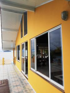 Casa amarilla con ventanas grandes y patio. en Mansão Ouro Verde Vlc Frente para o Mar com Piscina, en Piçarras