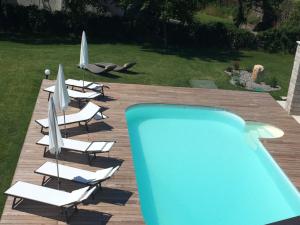 a group of chairs and umbrellas next to a swimming pool at B&B Sgonico in Sgonico