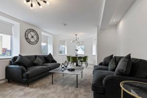 a living room with two couches and a clock on the wall at Mode Apartments Blackpool in Blackpool