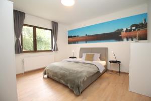 歐本的住宿－Oscappart，卧室配有一张床,墙上挂有绘画作品
