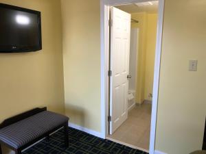 a room with a door and a bench and a television at Rosewood Motel in East Wareham