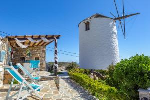 a windmill and lounge chairs in front of a house at Anemomylos-Windmill in Ermoupoli