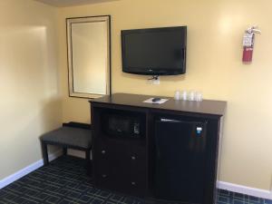 a room with a tv on the wall and a chair at Rosewood Motel in East Wareham