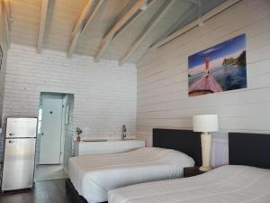 a white bedroom with two beds and a refrigerator at Hollywood Gardens Inn & Suites in Hollywood