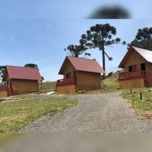 two wooden huts on a hill with a dirt road at Pousada Bela Tereza in São Joaquim