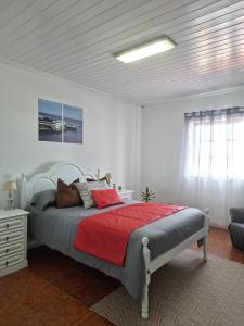 a bedroom with a bed with a red blanket at "Apartamentos do Farol" com vista para o mar in Santa Cruz das Flores