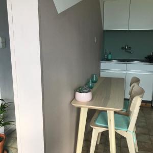 a small kitchen with a wooden table and chairs at Studio Bee Home in De Haan