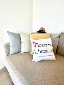 a hat sitting on a couch with a pillow that reads assumes at Vacances Arbanaises - Appartements Giens in Hyères