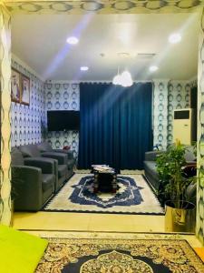 a living room with couches and a blue curtain at HALA HOTELS APARTMENTS in Sharjah