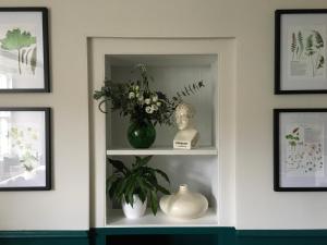 a white shelf with a vase and flowers on it at Bay Cottage & Bay Stables in Torpoint