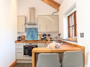 cocina con armarios blancos y mesa de madera en Rosewarrick Cottage, en Bodmin