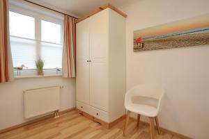 a room with a chair and a cabinet and a window at Feriendorf Papillon Wohnung 03-1 in Boltenhagen