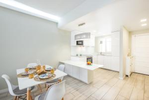 eine Küche mit weißen Schränken und einem Tisch und Stühlen in der Unterkunft Blue Star Luxury Apartment by Atlantic Places in Albufeira