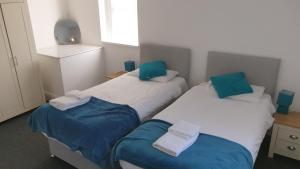 two beds in a room with blue and white at Coast Accommodation Station Road Apartments in Blackpool
