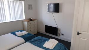 a small bedroom with two beds and a television at Coast Accommodation Station Road Apartments in Blackpool