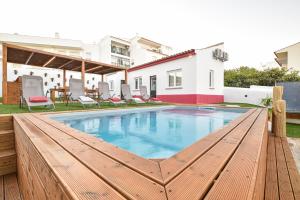 a pool with a wooden deck next to a house at Elevator's Beach House in Albufeira