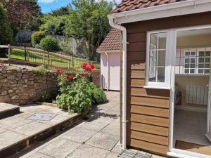 ein kleines Haus mit einem Fenster und einer Steinmauer in der Unterkunft Spacious family & dog friendly home from home with sea views and private garden in Porlock