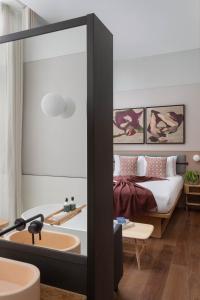 a hotel room with a bed, chair and a mirror at Inhabit, Queen's Gardens in London