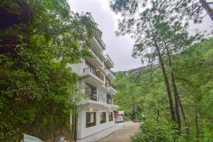 a white building in the middle of a forest at Hotel The Paal in Shimla