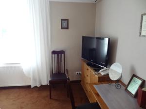 a living room with a flat screen tv and a chair at Pensjonat U Kota Wasyla in Chodzież
