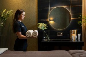 a woman standing in a hotel room holding towels at Lure Hotel & Spa - Adults Only in Mellieħa