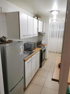 Una cocina con gabinetes blancos y una estufa. en Depto Maqui, en Puerto Montt