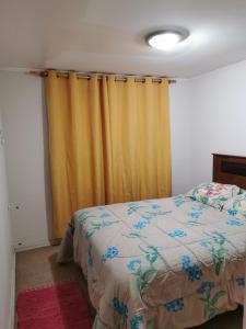 1 dormitorio con cama y cortina amarilla en Depto Maqui, en Puerto Montt