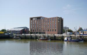 a group of boats docked in the water near a building at havenhostel Cuxhaven in Cuxhaven