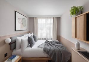 een slaapkamer met een bed met kussens en een raam bij Inhabit Queen's Gardens, a Member of Design Hotels in Londen