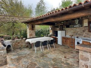 an outdoor kitchen with a white table and chairs at Apartamentos Alburiñas Ribeira Sacra in Bolmente