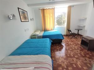 1 dormitorio con 2 camas, mesa y ventana en Icthus Paracas, en Paracas