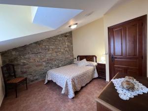 a bedroom with a bed and a stone wall at La Casina Del Rio in Argovejo
