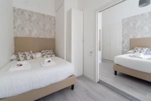 a white bedroom with two beds and a mirror at White Gioberti Guesthouse in Rome