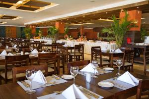 un restaurante con mesas de madera y sillas con servilletas blancas en Gran Hotel Stella Maris Urban Resort & Conventions en Salvador