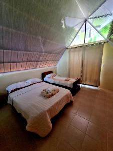 - une chambre avec 2 lits et une grande fenêtre dans l'établissement Ballena Oasis Homes (Chalets con AC), à Uvita