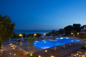 a swimming pool at night with chairs and tables at Negroponte Resort Eretria in Eretria