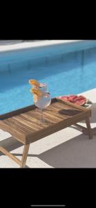 una mesa de madera con una copa de vino sentada junto a una piscina en Villa Iva Vodice en Vodice