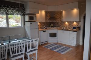 una cocina con electrodomésticos blancos, mesa y sillas en Hazel Ridge, en Hudiksvall