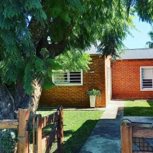 a brick house with a tree and a fence at Eljacaranda_ in Gualeguay