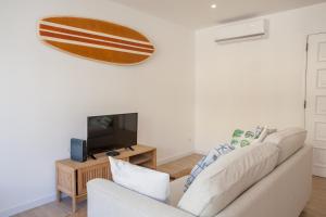 a living room with a couch and a tv at Sea, Surf & The City-RENOVATED APRIL 2022 in Costa da Caparica