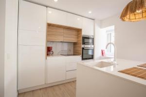 a white kitchen with white cabinets and a sink at Sea, Surf & The City-RENOVATED APRIL 2022 in Costa da Caparica