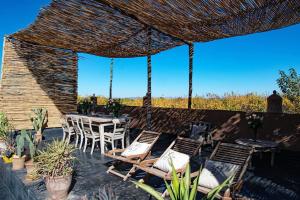 a patio with chairs and a table and a straw umbrella at Aux portes de Marrakech Villa Arts & Déco avec piscine in Marrakech