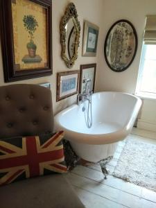 a bathroom with a tub and a mirror and a chair at Cosy, dog friendly house on the fringe of the Brecon Beacons in Tredegar