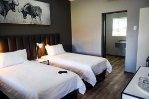 Grey Goose Game Lodge في نيوكاسل: غرفة فندقية بسريرين ومرآة
