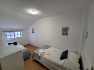 a small room with two beds and a window at Alojamento Rosa in Nazaré