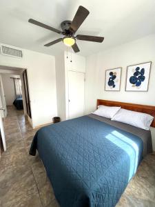 1 dormitorio con 1 cama azul y ventilador de techo en Departamento Los Cedros en Ciudad Juárez