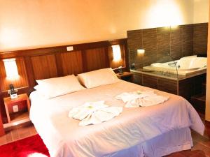 a bedroom with a large white bed with towels on it at Hospedagem Spa da Alma in Monte Verde