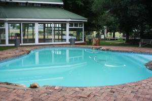 a swimming pool with blue water in front of a building at Grey Goose Game Lodge in Newcastle