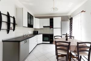 uma cozinha com armários brancos e uma mesa e cadeiras em Apartment Marica em Lopar